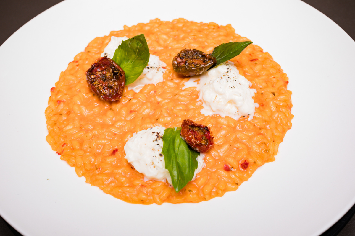 Risotto &agrave; la tomate s&eacute;ch&eacute;e et mozzarella, d&eacute;cor&eacute; de basilic frais.