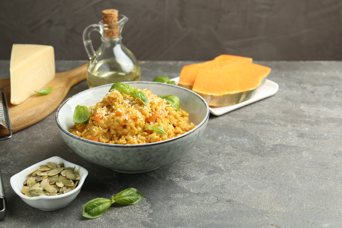 Bol de risotto au potiron, garni de parmesan r&acirc;p&eacute; et de basilic frais.