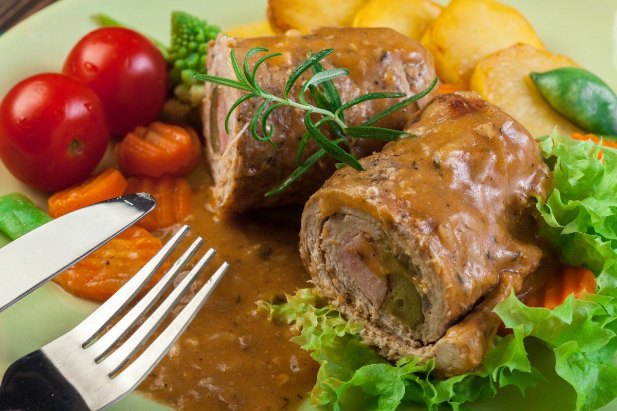 Roulades de porc en sauce servies avec des légumes et des pommes de terre.