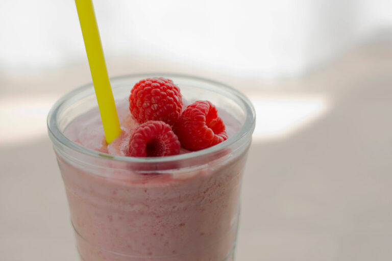 Milkshake à la framboise dans un verre, garni de framboises fraîches.