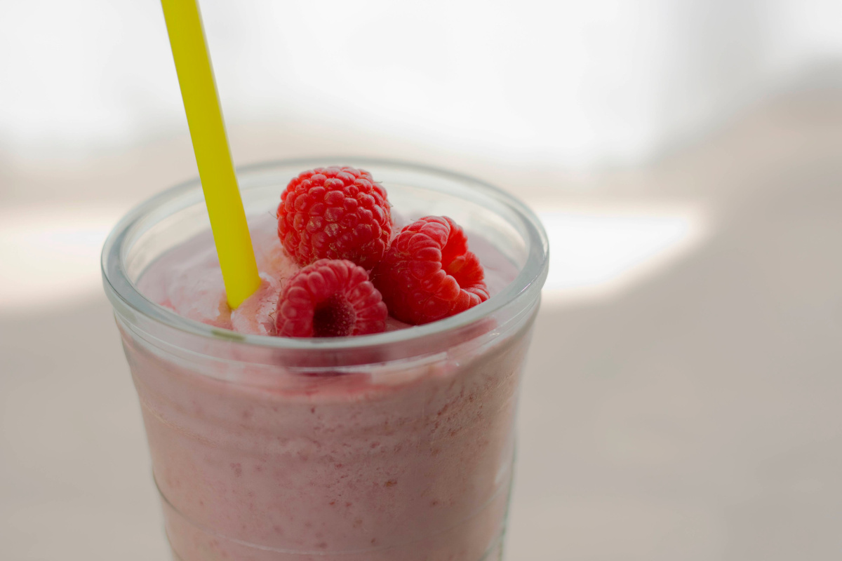 Milkshake &agrave; la framboise dans un verre, garni de framboises fra&icirc;ches.
