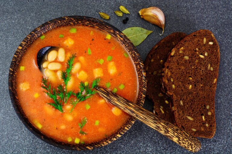Bol de soupe sicilienne à la tomate et haricots blancs avec du pain noir.