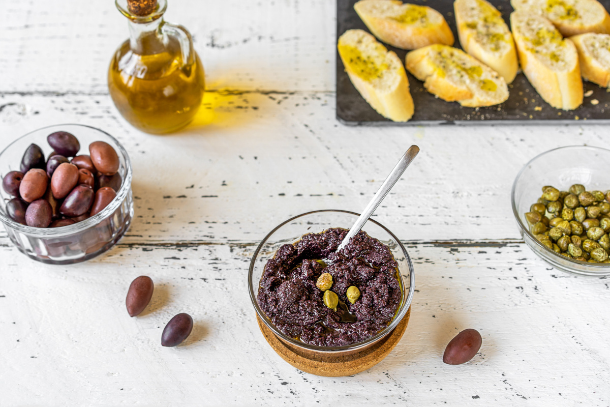 Tapenade aux olives noires et c&acirc;pres en deco, avec des toasts grill&eacute;s.