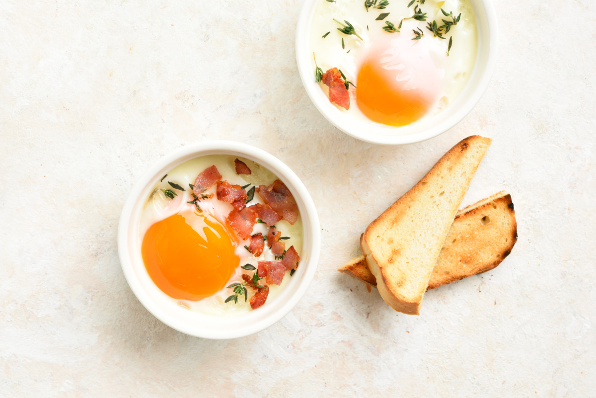 Ramequins d'&oelig;ufs cocotte au jambon sec et thym, servis avec des mouillettes grill&eacute;es.