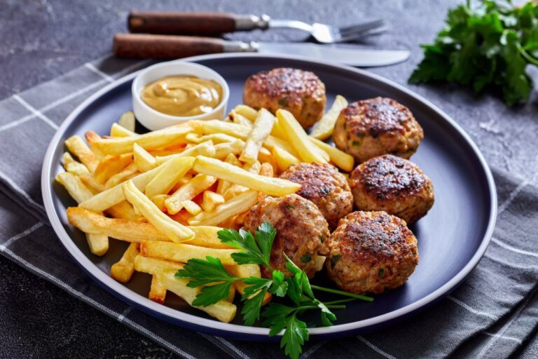Assiette de vitoulets, boulettes belges, servies avec des frites et de la moutarde.