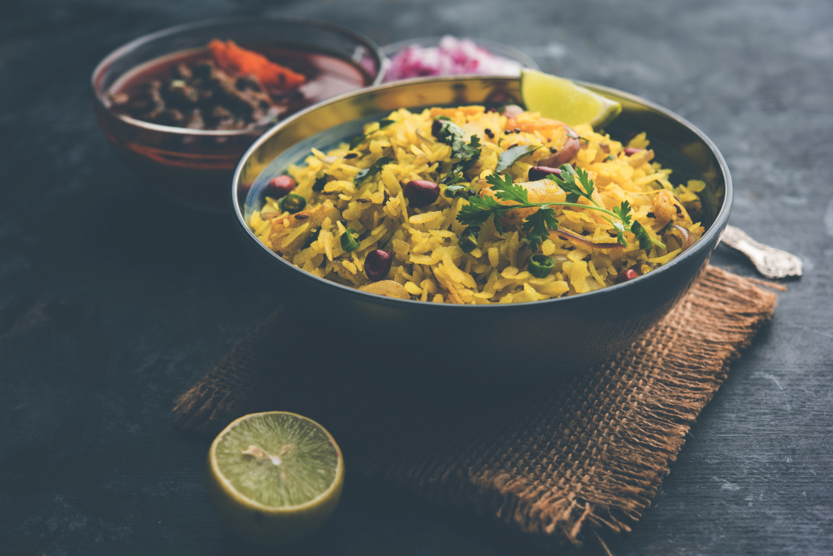 Plat indien de Aloo Kanda Poha servi avec un curry épicé et du citron.