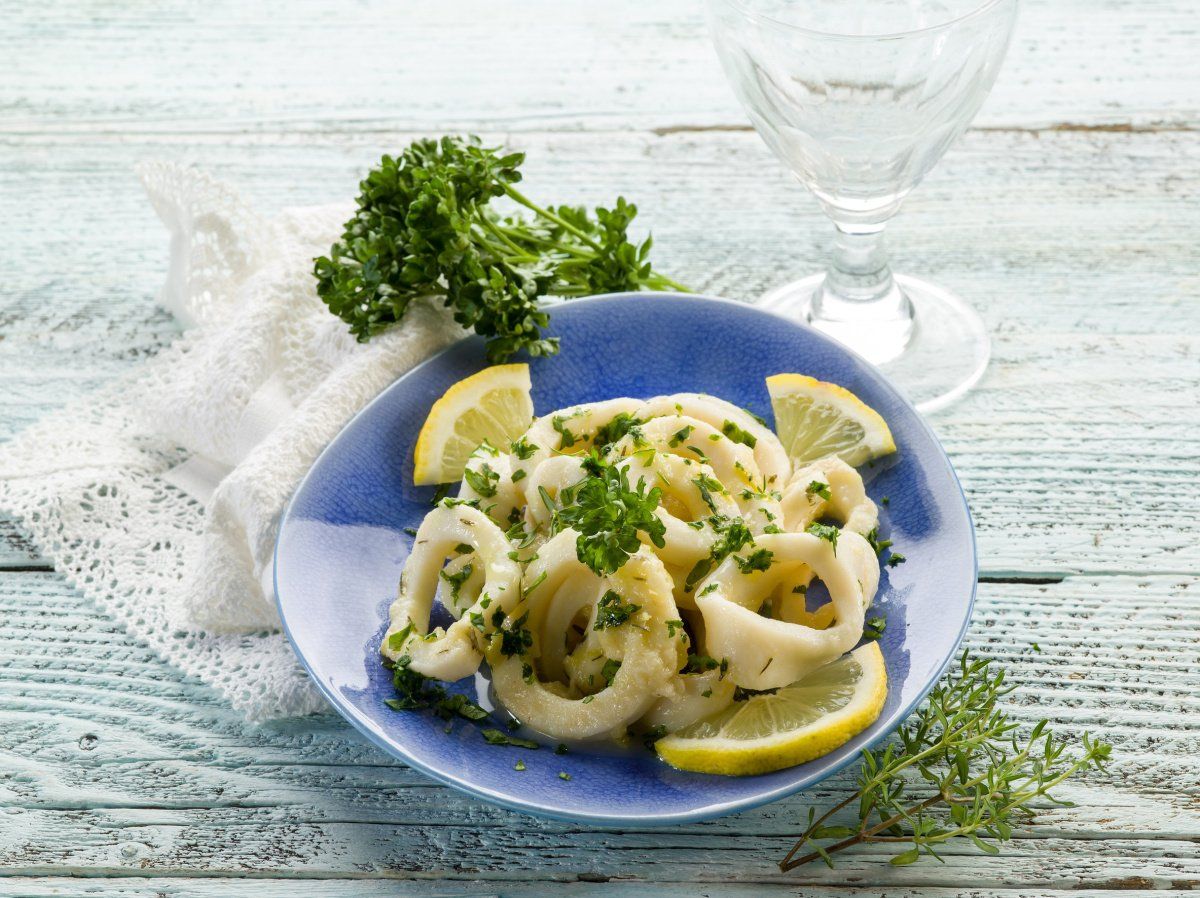 Anneaux de calamar cuisin&eacute;s en persillade avec des quartiers de citron jaune.
