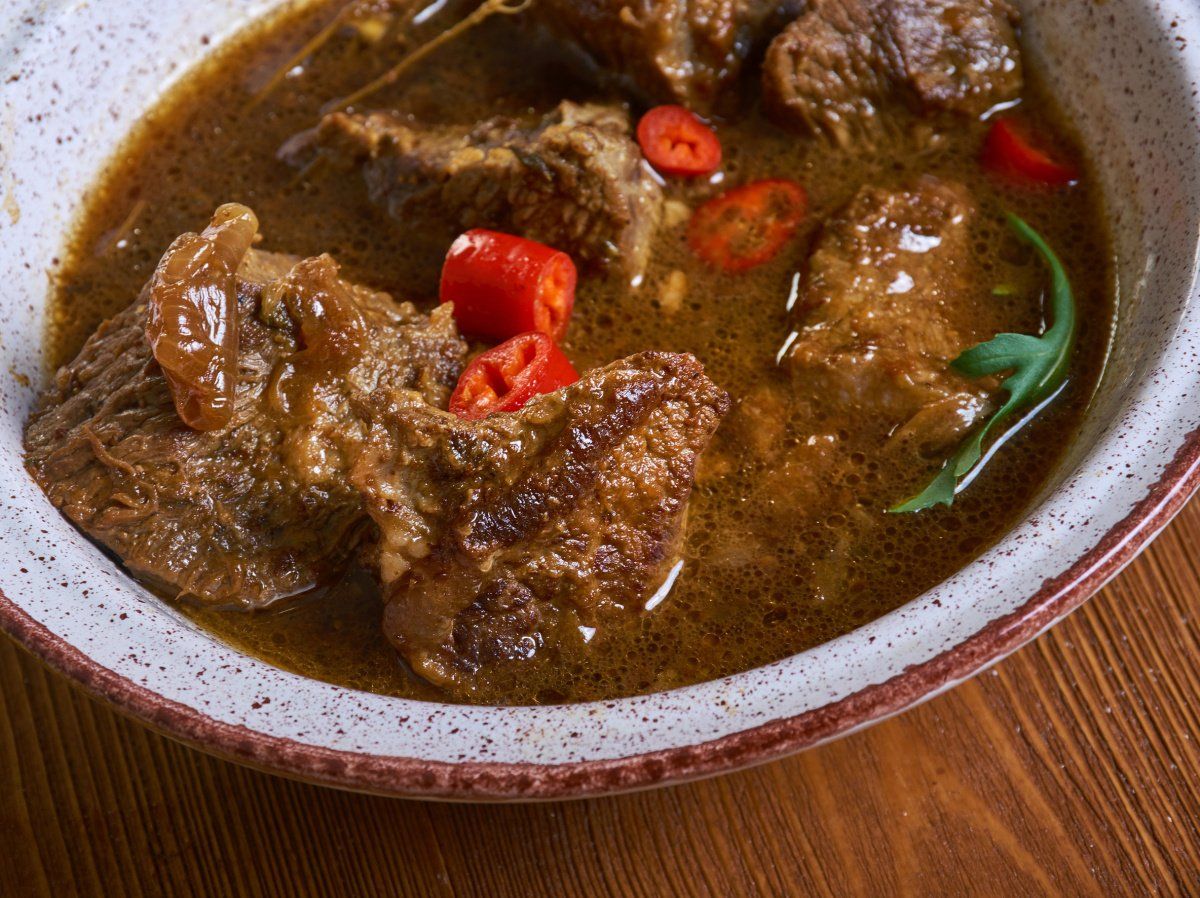 Rago&ucirc;t d'agneau tchadien Bangaou mijot&eacute; dans sa sauce et garni de piments rouges.