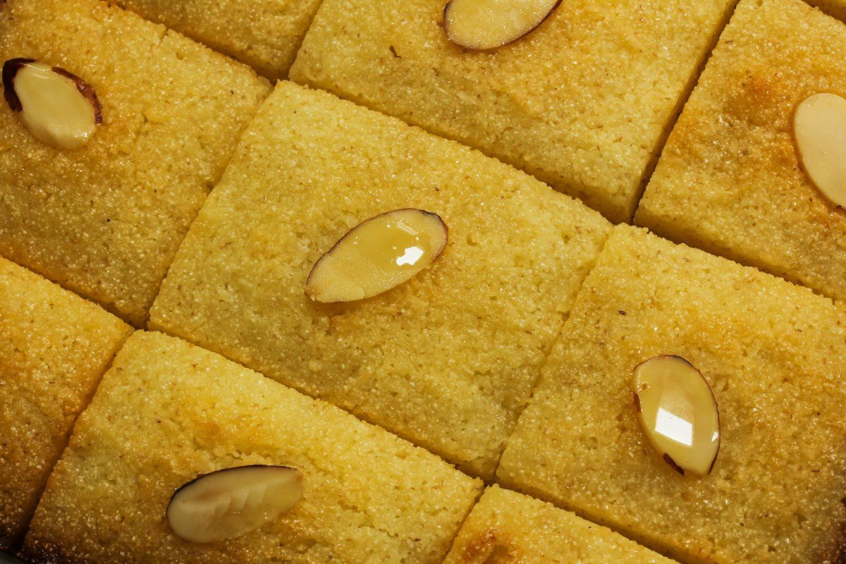 G&acirc;teau de semoule basbousa dor&eacute;, d&eacute;coup&eacute; en losanges et garni d'amandes effil&eacute;es.