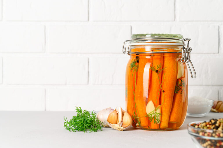 Bocal en verre de carottes fermentées maison avec ail, aneth et grains de poivre.