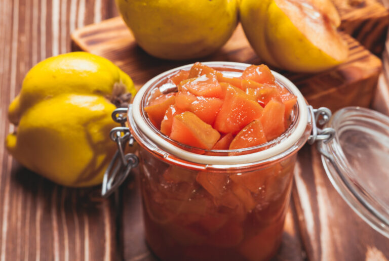 Confiture de coings maison en morceaux dans un bocal avec des fruits frais.