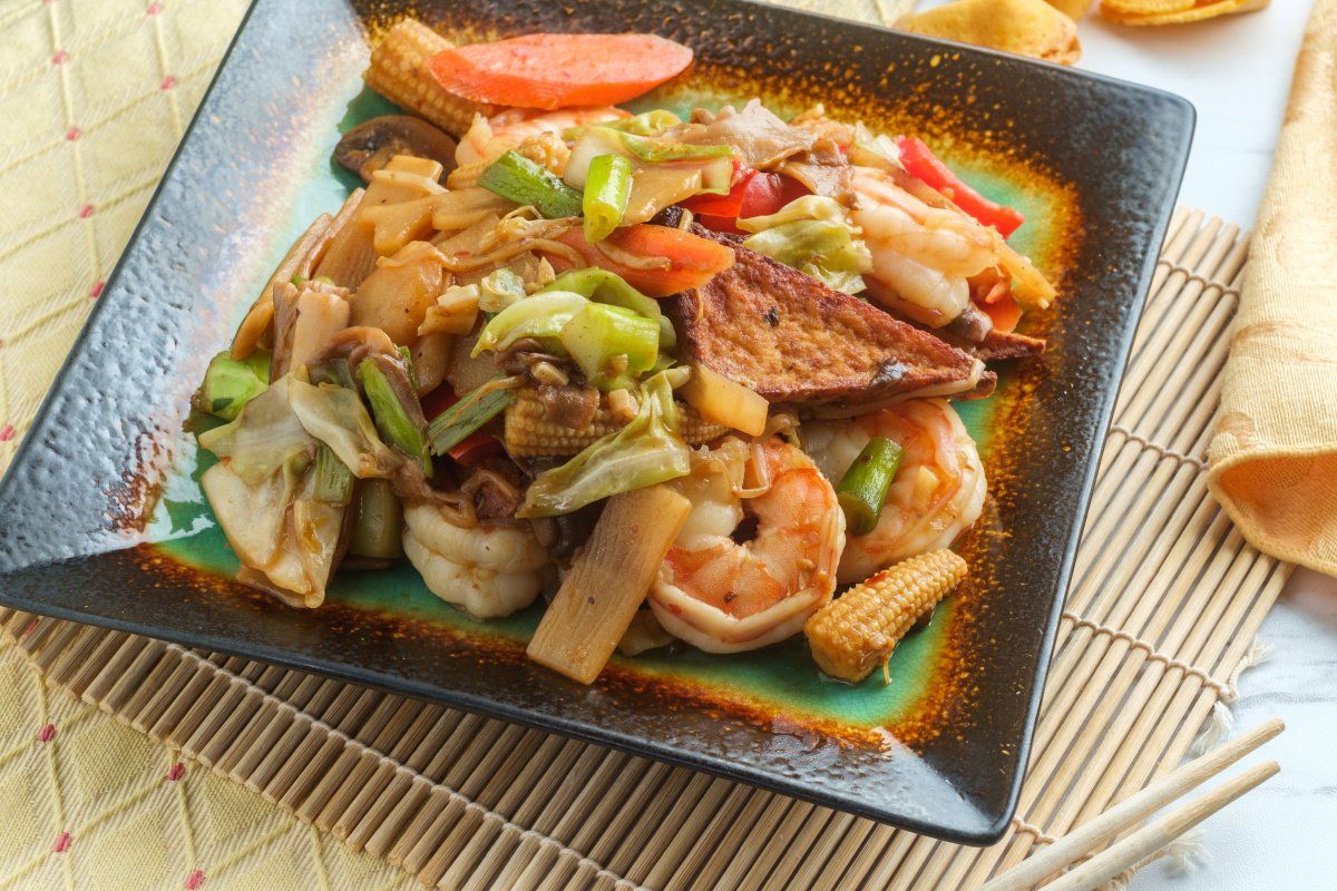 Plat de crevettes sautées et légumes, servi dans une assiette.