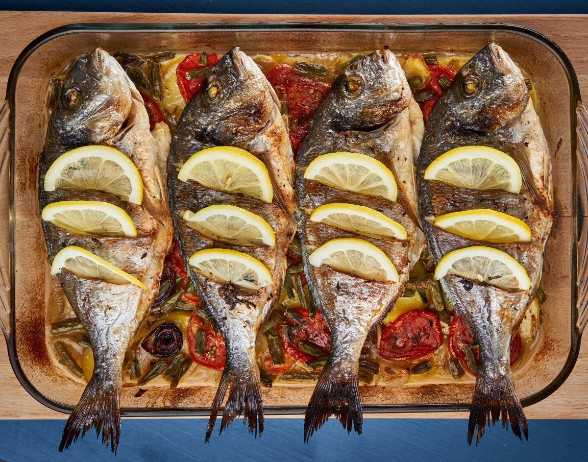 Plat de daurades enti&egrave;res au citron au four sur un lit de l&eacute;gumes.