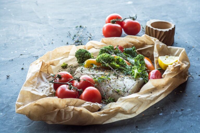Cabillaud en papillote avec tomates, broccolini, citron et thym sur papier cuisson.