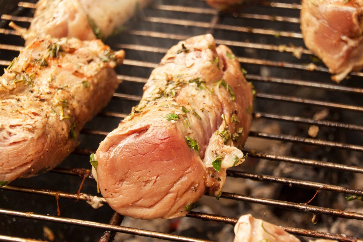Filet mignon de porc marin&eacute; aux herbes cuisant sur la grille du barbecue.