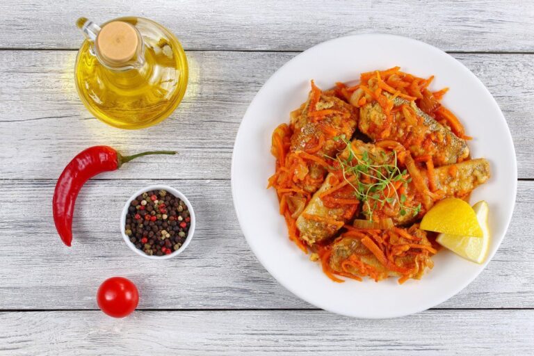 Filets de poisson mijoté aux carottes et oignons dans une sauce, garni de thym frais.
