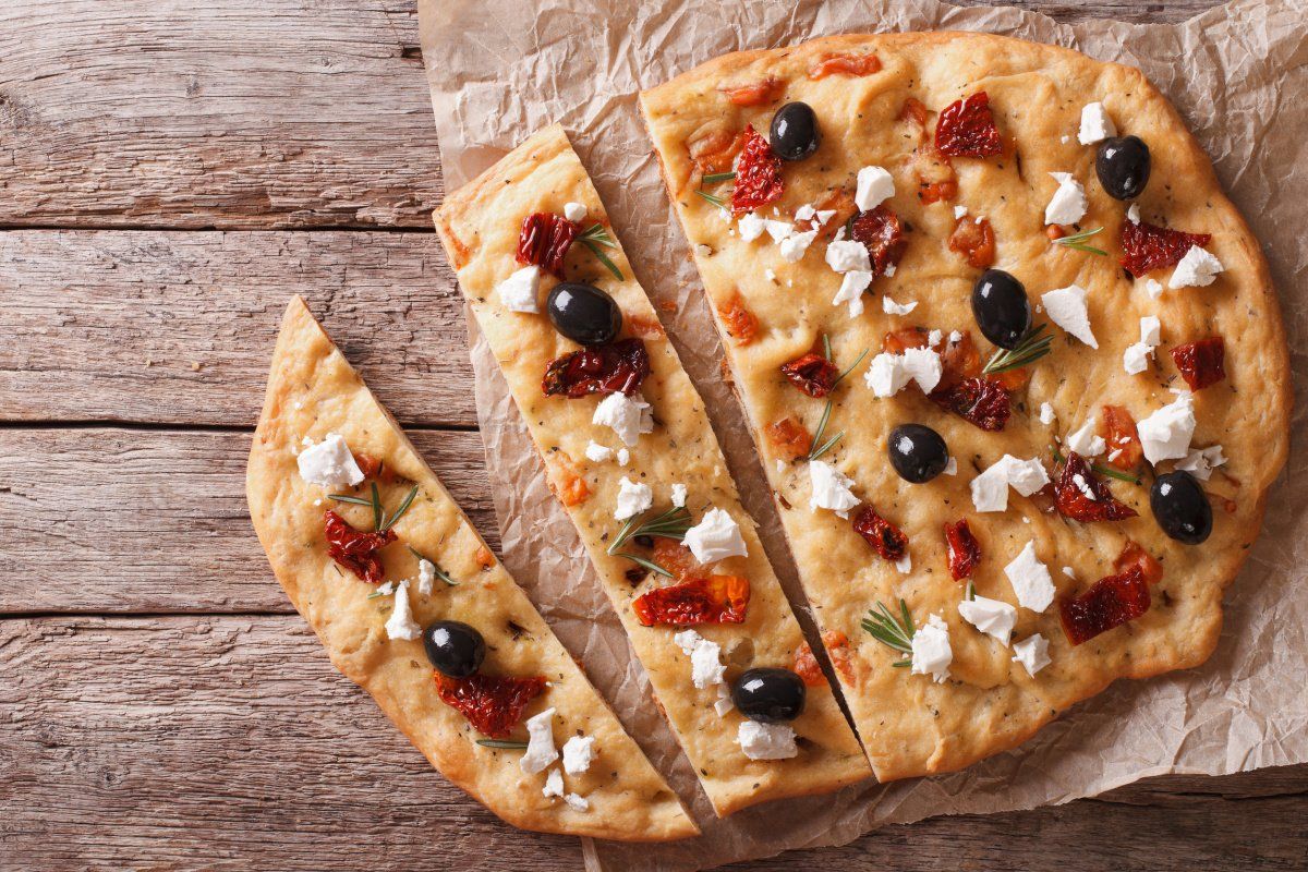 Focaccia aux tomates s&eacute;ch&eacute;es, feta et olives, coup&eacute;e en parts.