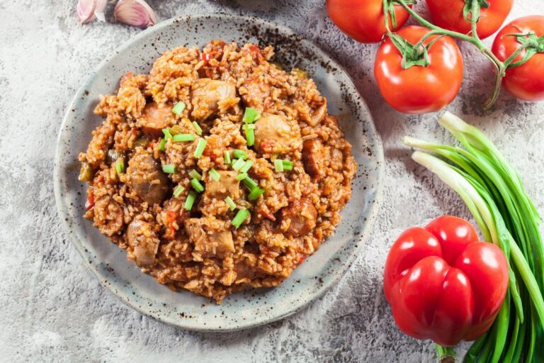 Jambalaya épicé au poulet et à la saucisse, garni de ciboule fraîche.