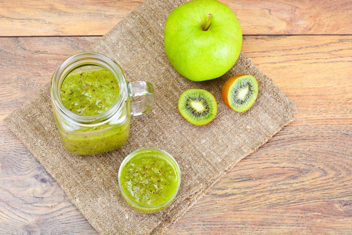 Jus vert de kiwi et pomme dans un bocal avec les fruits frais &agrave; c&ocirc;t&eacute;.