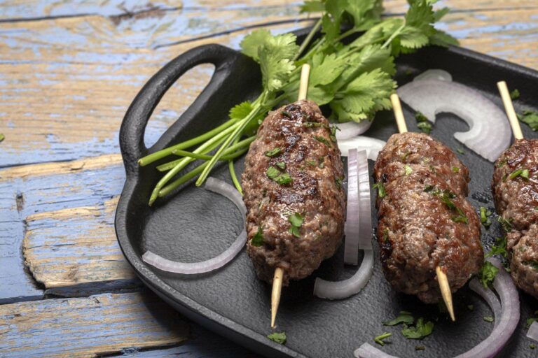 Kefta de boeuf grillées servies avec coriandre fraîche et oignon rouge.