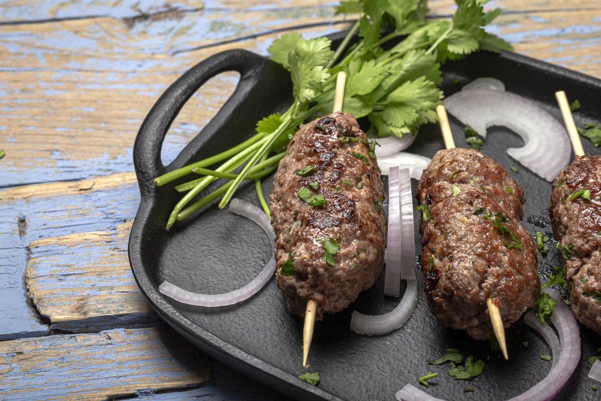 Kefta de boeuf grill&eacute;es servies avec coriandre fra&icirc;che et oignon rouge.