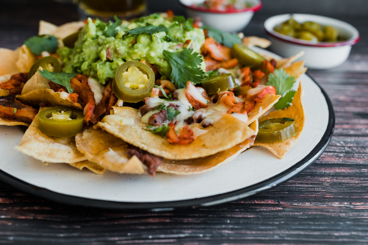 Nachos mexicains garnis de guacamole, fromage, jalape&ntilde;os et coriandre.