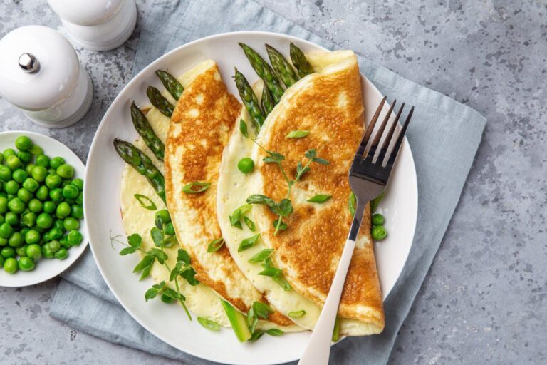 Omelette dorée pliée aux asperges vertes, petits pois et pousses de pois fraîches.