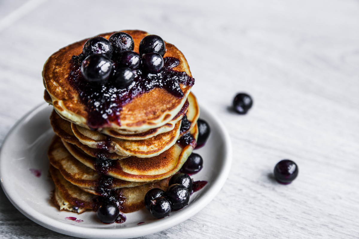 Pile de pancakes dor&eacute;s garnis de confiture et de cassis frais.