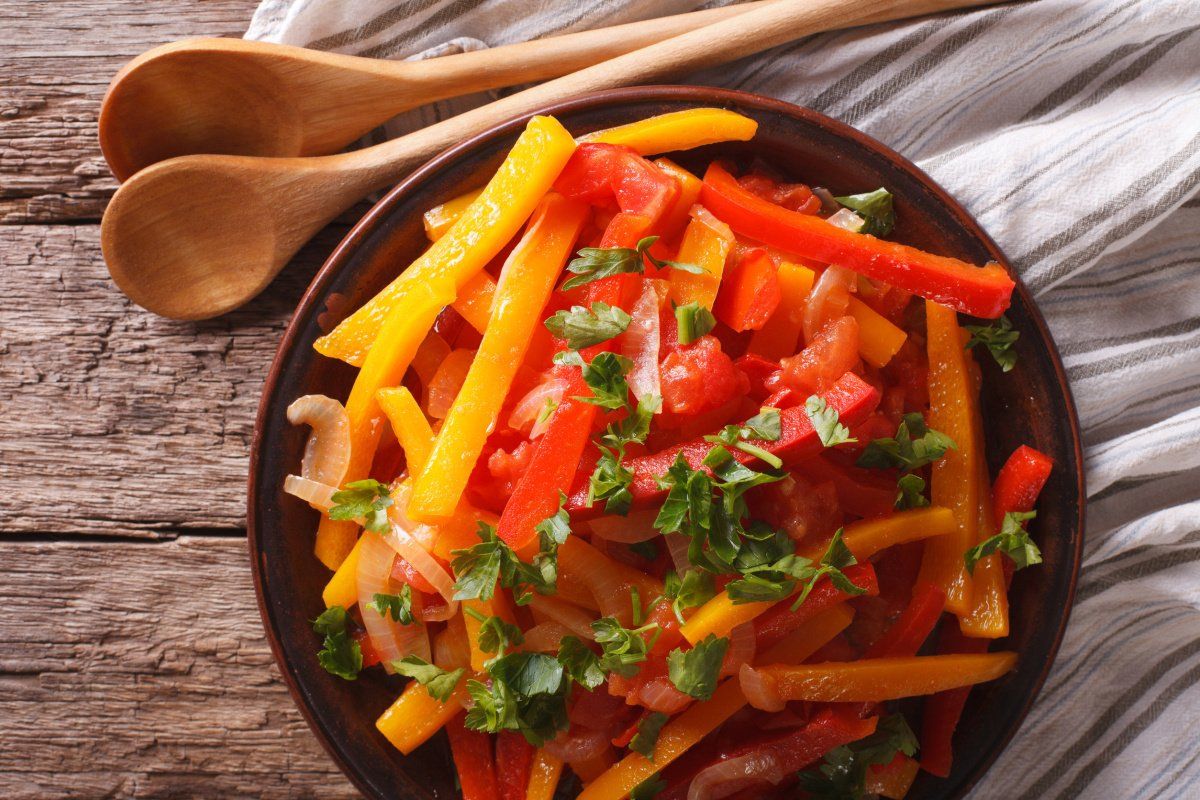 Plat de piperade basque traditionnelle avec poivrons, tomates, oignons et persil frais.