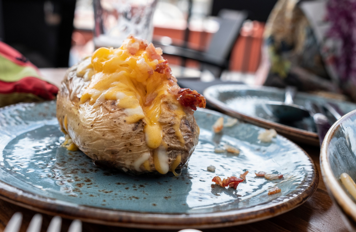 Pomme de terre au four r&ocirc;tie, garnie de cheddar fondu et de bacon.