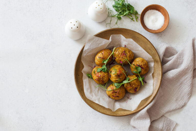 Pommes de terre Hasselback dorées au four, garnies de jeunes pousses fraîches.