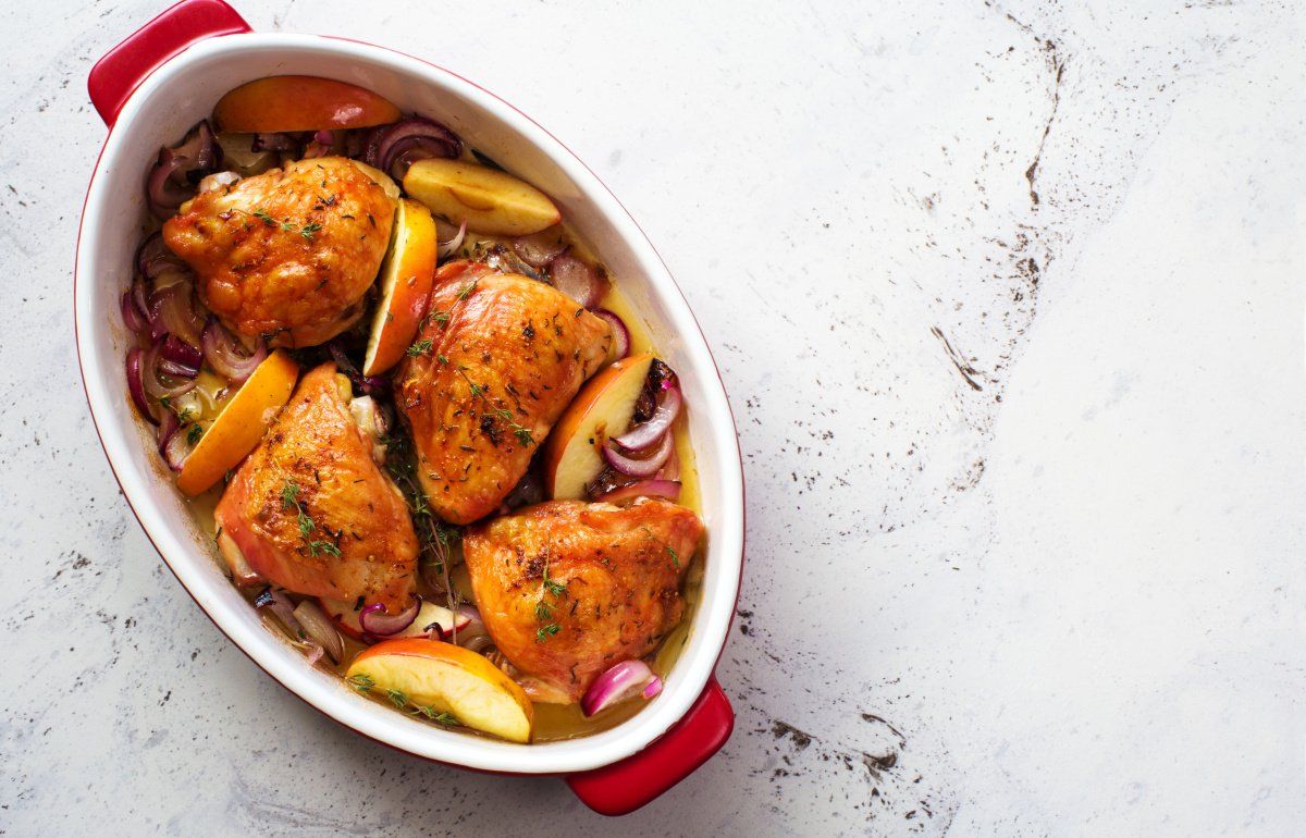 Hauts de cuisses de poulet au four avec pommes et oignons rouges.
