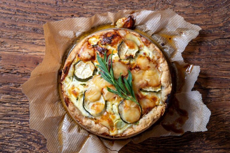 Quiche aux courgettes et aux poireaux avec du fromage gratiné, avec une branche d'estragon.