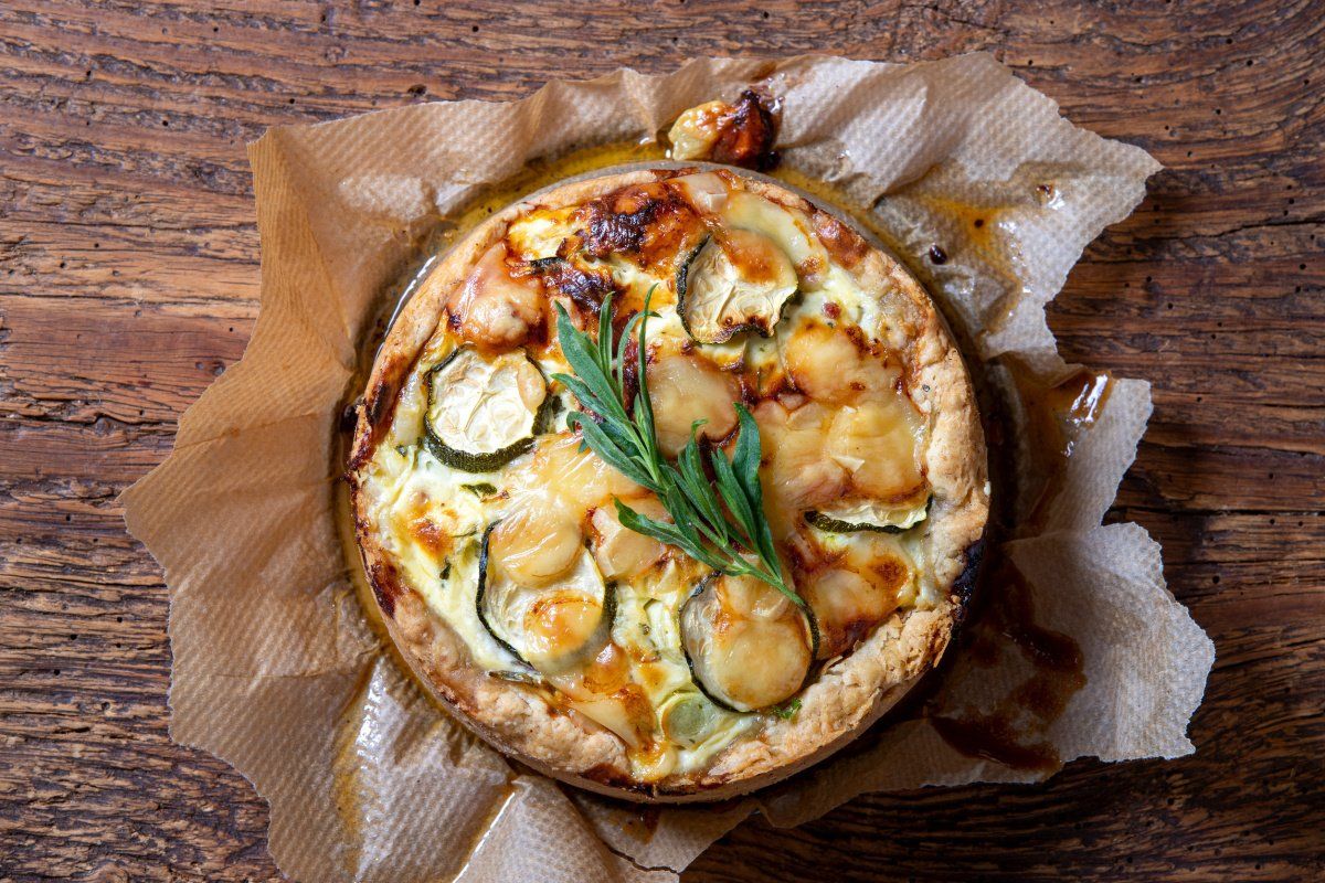Quiche aux courgettes et aux poireaux avec du fromage gratiné, avec une branche d'estragon.