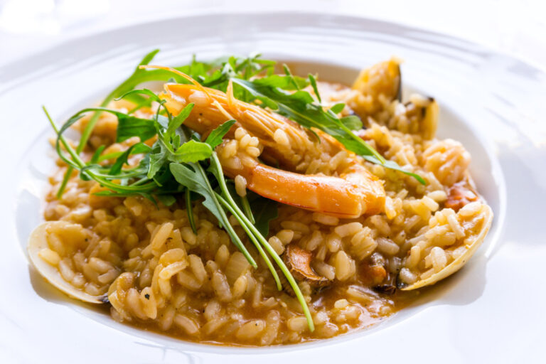 Risotto crémeux aux crevettes et coquillages, garni de roquette.