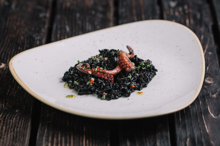 Risotto noir à l'encre de seiche garni d'un tentacule de poulpe grillé.