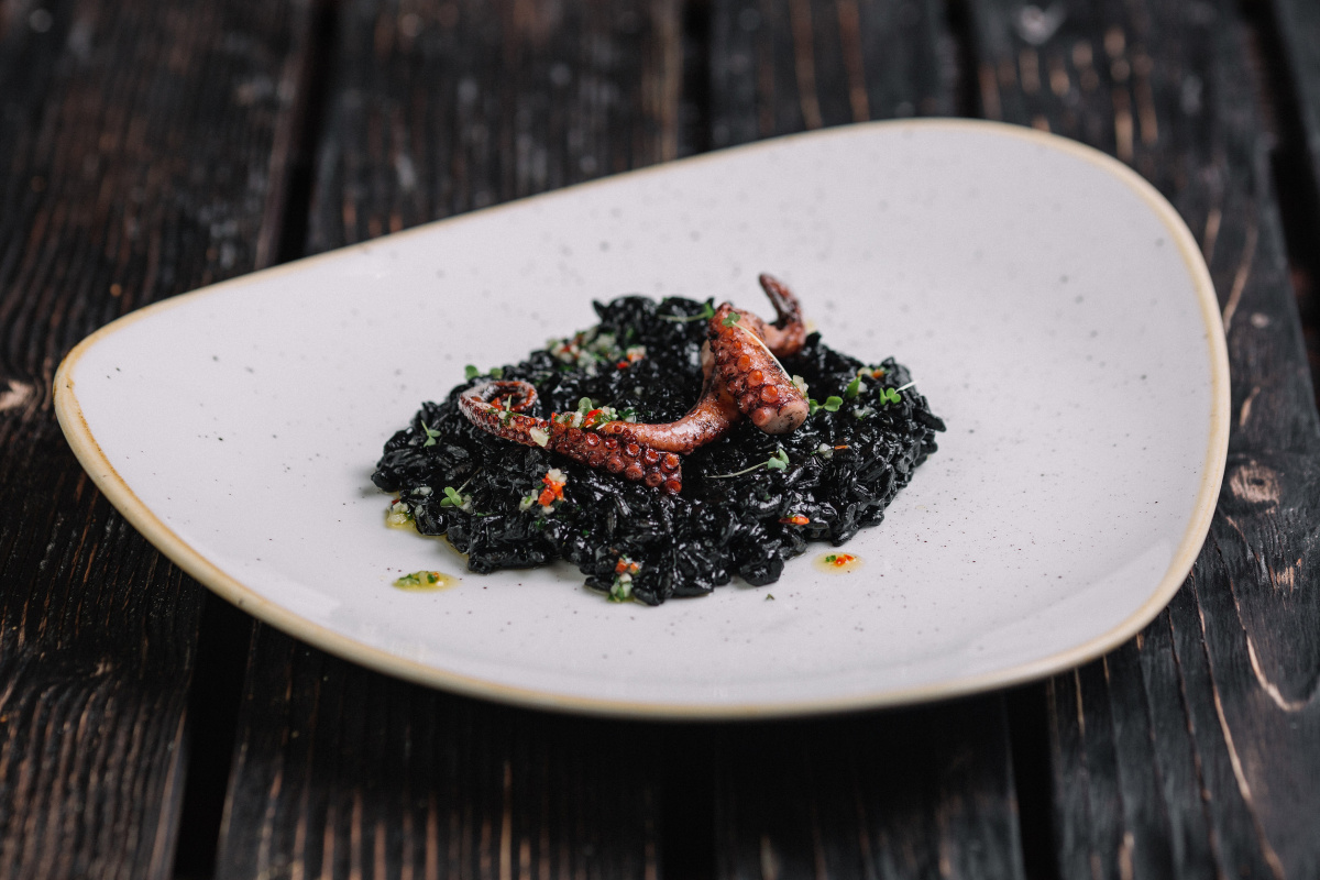 Risotto noir &agrave; l'encre de seiche garni d'un tentacule de poulpe grill&eacute;.