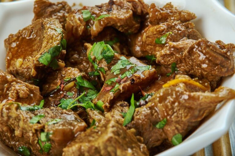 Saksang, un ragoût de viande épicé en sauce, garni d'herbes fraîches ciselées.