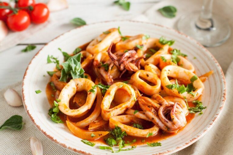 Salade de calamars et poulpe en sauce tomate, garnie d'herbes fraîches.