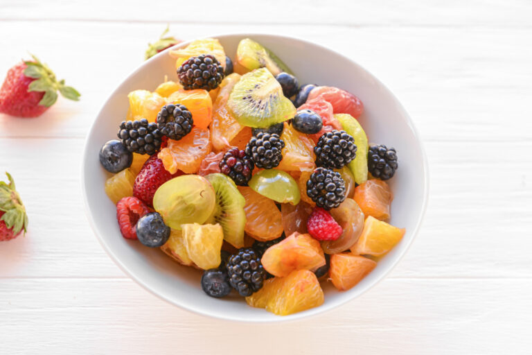 Salade de fruits frais colorée avec mûres, oranges, kiwis et fruits rouges.