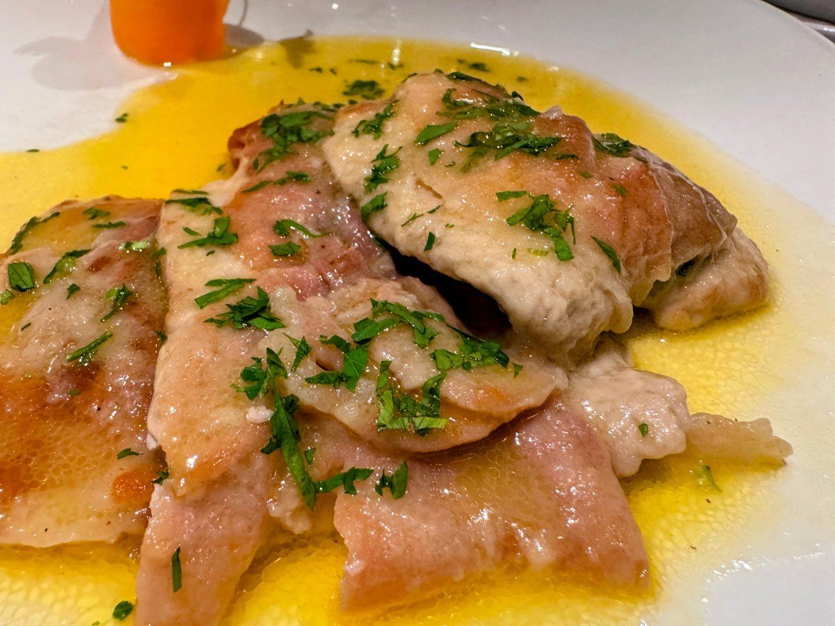 Saltimbocca de veau napp&eacute;s d'une sauce au beurre et parsem&eacute;s de basilic frais.