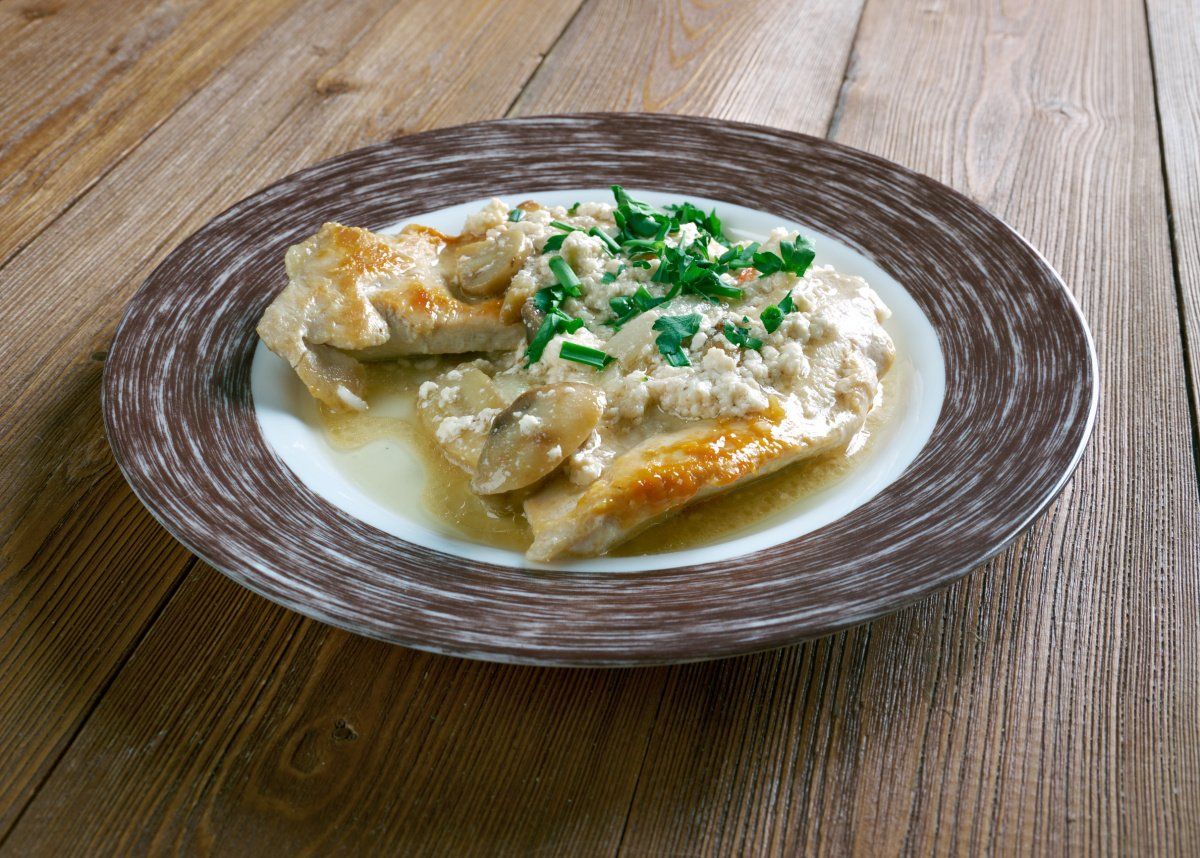 Plat de scaloppine de viande en sauce cr&eacute;meuse aux champignons et herbes hach&eacute;es.