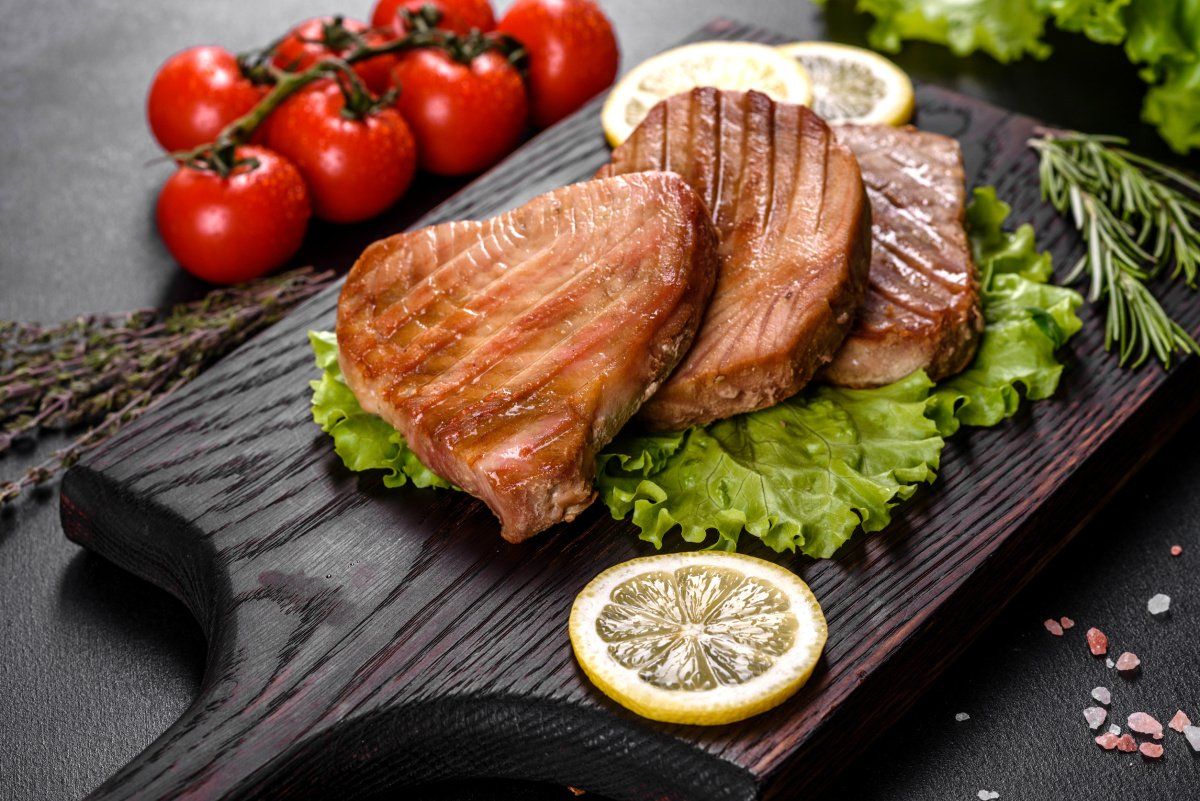 Steaks de thon grill&eacute;s juteux servis avec du citron et des herbes aromatiques.