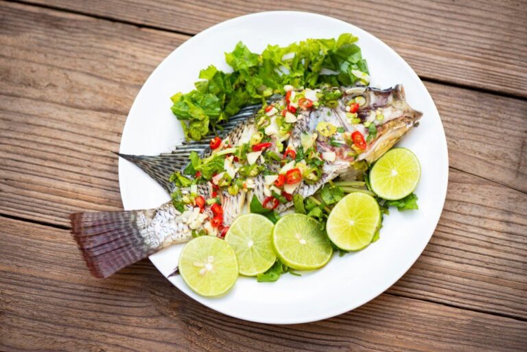 Poisson tilapia entier à la vapeur garni de piment, ail et tranches de citron vert.