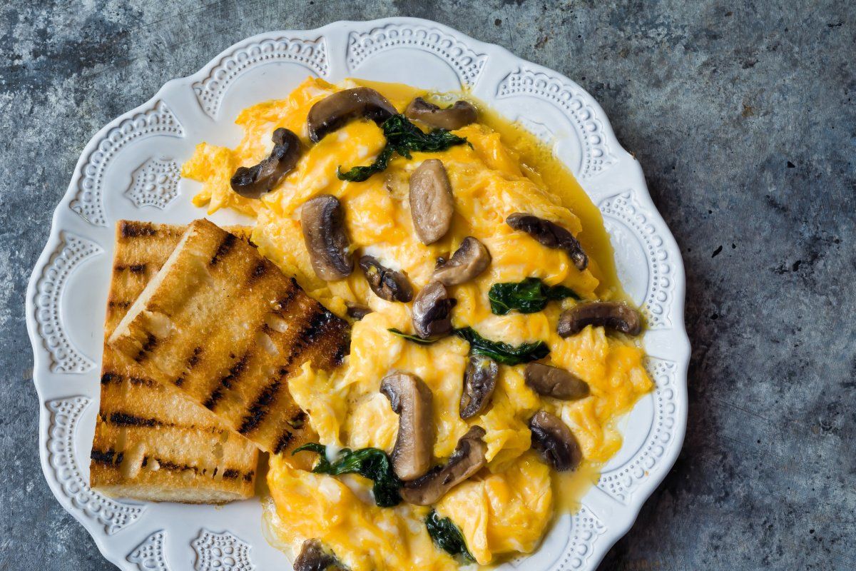 &OElig;ufs brouill&eacute;s aux champignons et &eacute;pinards, accompagn&eacute;s de pain grill&eacute;.