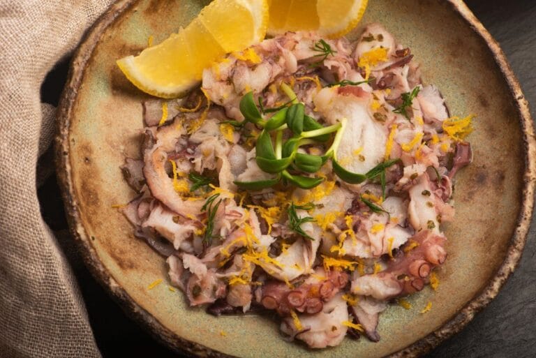 Carpaccio de poulpe finement tranché, assaisonné au citron, et aux zestes d'orange.s.