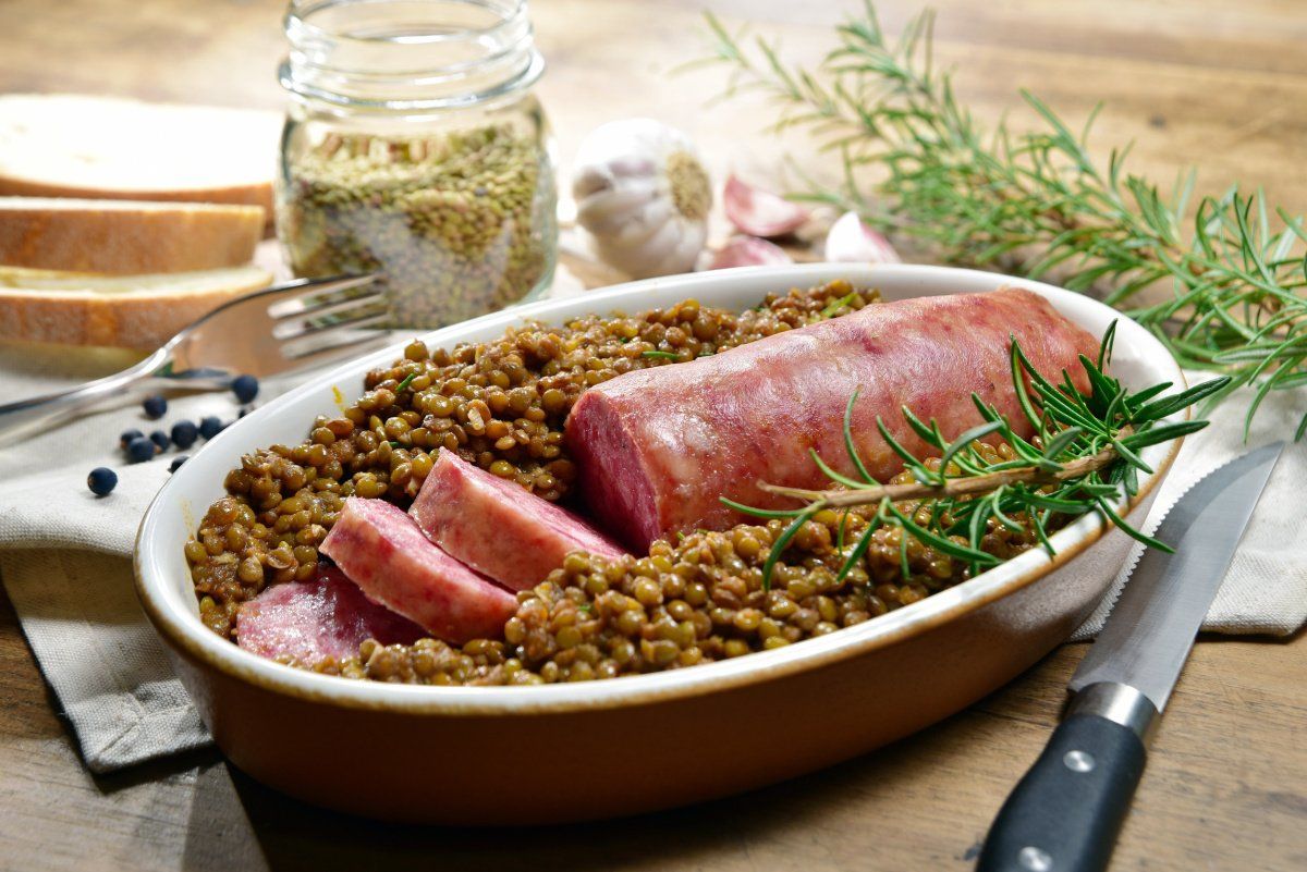 Plat de cotechino tranch&eacute; servi sur un lit de lentilles mijot&eacute;es.