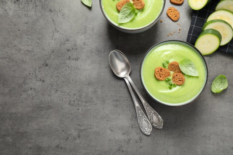 Crème de courgettes veloutée servie avec des croûtons et du basilic frais.