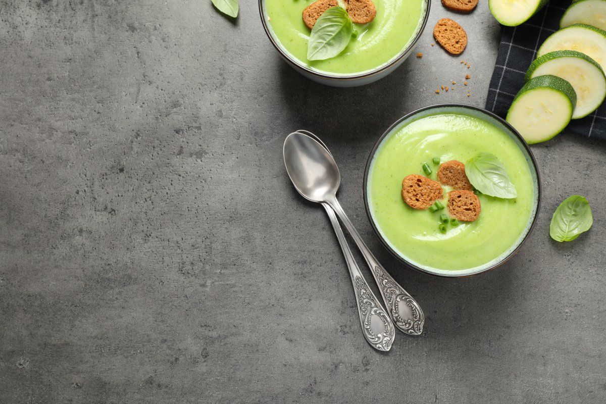 Cr&egrave;me de courgettes velout&eacute;e servie avec des cro&ucirc;tons et du basilic frais.