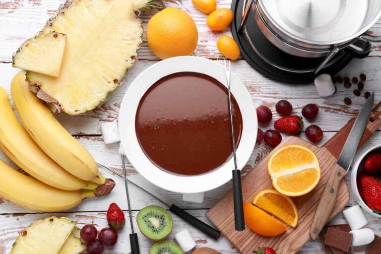 Fondue au chocolat servie avec une sélection de fruits frais et guimauves.